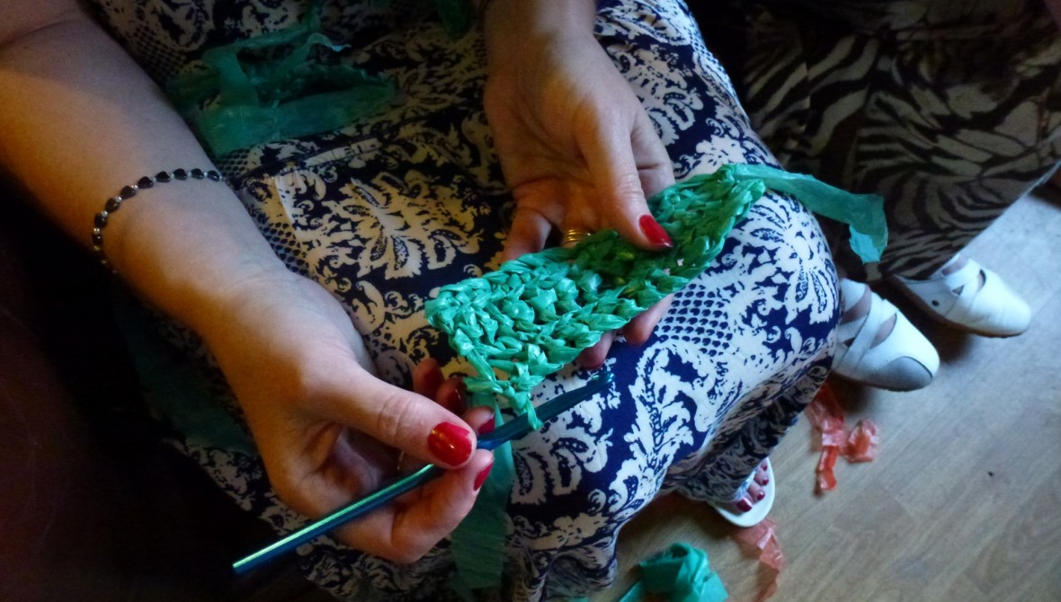 A person crochets with plastic.
